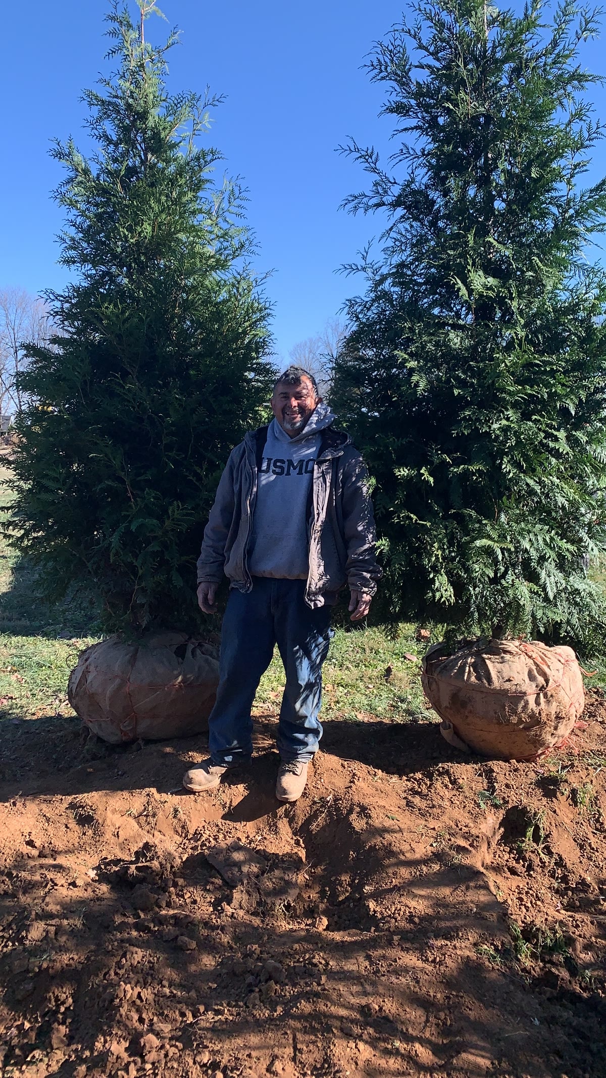 Orlando standing between two large trees at a Kentucky worksite